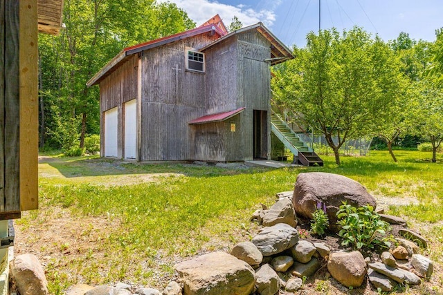 22 Woodpecker Ln, Embden, ME 04958 - view of home's exterior featuring stairs, a detached garage, an outbuilding, and a lawn
