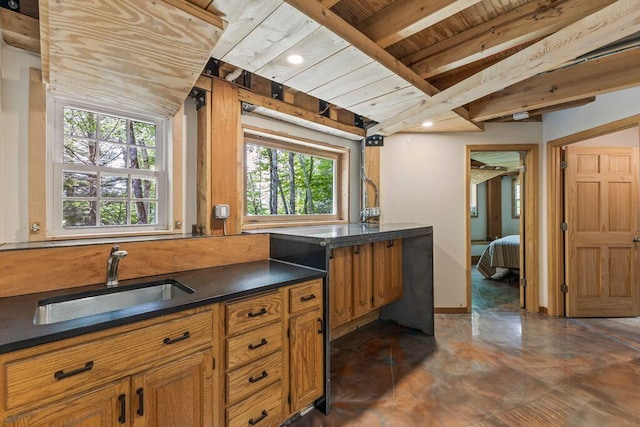 22 Woodpecker Ln, Embden, ME 04958 - kitchen with a wooden ceiling with exposed beams, dark countertops, and brown cabinets