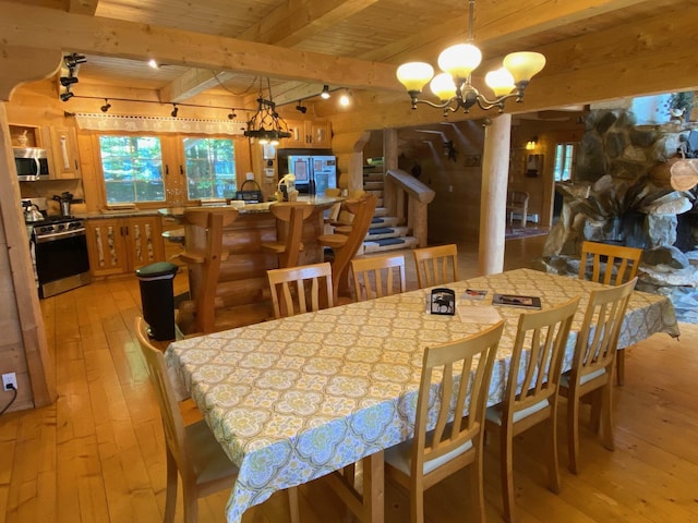 378 Black Point Rd, Beaver Cove, ME 04441 - dining room with light wood finished floors, a chandelier, a wooden ceiling with exposed beams, and stairs