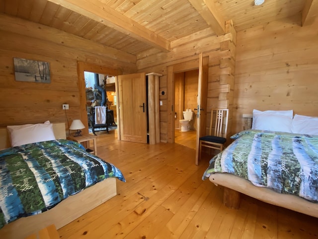 378 Black Point Rd, Beaver Cove, ME 04441 - bedroom with wooden walls, a wood ceiling with exposed beams, light wood finished floors, and ensuite bath