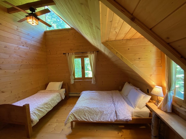 378 Black Point Rd, Beaver Cove, ME 04441 - bedroom featuring wooden ceiling, a baseboard heating unit, light wood finished floors, and wooden walls