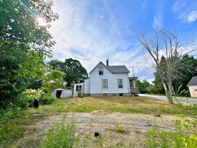 363 Lisbon St, Lisbon, ME 04250 - view of side of property featuring a storage unit, driveway, and a chimney