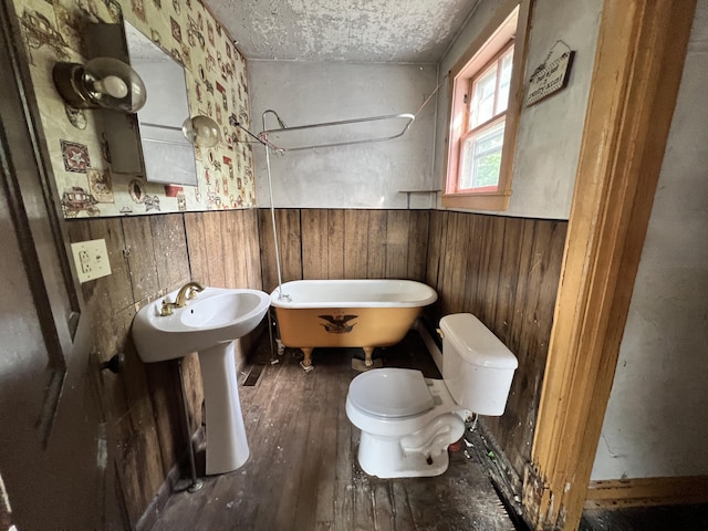 363 Lisbon St, Lisbon, ME 04250 - bathroom featuring a soaking tub, a wainscoted wall, hardwood / wood-style floors, wood walls, and a textured ceiling