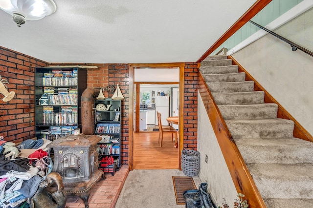 350 Cushing Rd, Cushing, ME 04563 - stairs featuring brick wall, a textured ceiling, and a wood stove