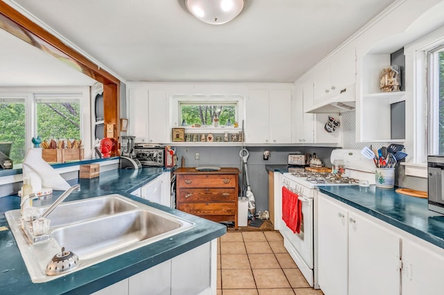 350 Cushing Rd, Cushing, ME 04563 - kitchen with white stove, under cabinet range hood, dark countertops, white cabinetry, and light tile patterned floors