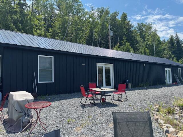 42 Applehead Way, Orrington, ME 04474 - rear view of property featuring board and batten siding, a patio area, and a metal roof