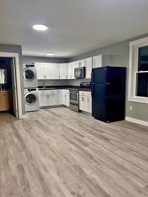 42 Applehead Way, Orrington, ME 04474 - kitchen featuring black appliances, estacked washer and dryer, dark countertops, white cabinets, and light wood finished floors