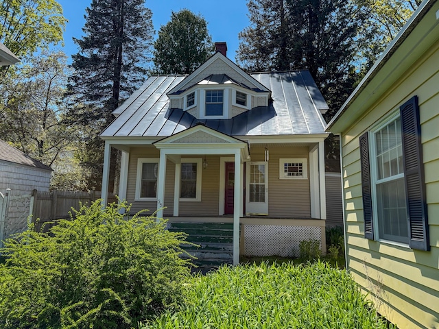 35 Washington St, Rumford, ME 04276 - view of front facade featuring a standing seam roof, covered porch, a metal roof, and a chimney