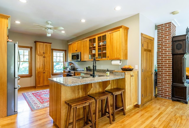 270 Park St, Rockport, ME 04856 - kitchen featuring appliances with stainless steel finishes, ceiling fan, light stone counters, light wood-style floors, and a peninsula