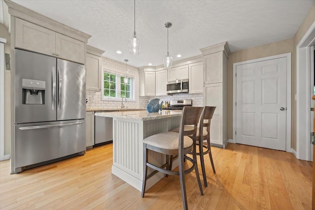 7 Coastal Woods Dr Unit 102, Kennebunk, ME 04043 - kitchen with stainless steel appliances, decorative backsplash, light wood-type flooring, recessed lighting, and a textured ceiling