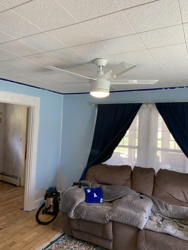 9 Coolidge St, Livermore, ME 04253 - living area featuring a baseboard radiator, wood finished floors, a drop ceiling, and a ceiling fan