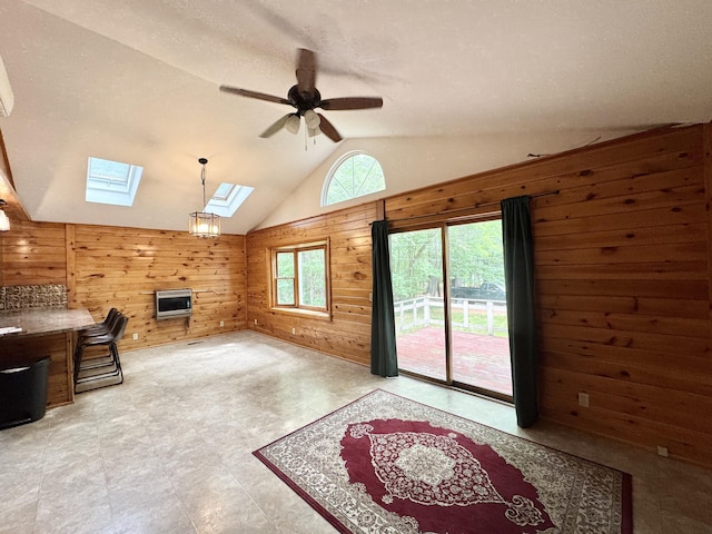 24 N Tiery St, Old Town, ME 04468 - unfurnished living room featuring wooden walls, a skylight, lofted ceiling, ceiling fan, and heating unit