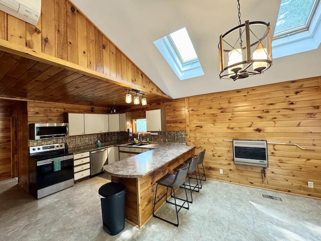 24 N Tiery St, Old Town, ME 04468 - kitchen featuring a skylight, stainless steel appliances, heating unit, a peninsula, and wood walls