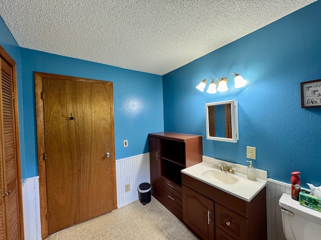 24 N Tiery St, Old Town, ME 04468 - bathroom with wainscoting, a textured ceiling, vanity, and a closet