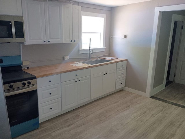 44 Baldwin St, Livermore Falls, ME 04254 - kitchen featuring stainless steel appliances, wooden counters, light wood-style floors, and white cabinetry