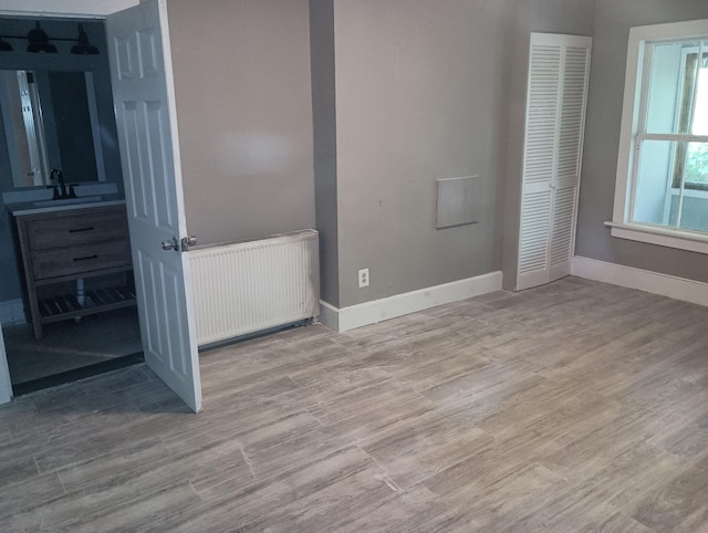 44 Baldwin St, Livermore Falls, ME 04254 - unfurnished bedroom with radiator heating unit, wood finished floors, and a closet
