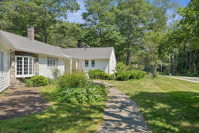 53 Beach Ave, Kennebunk, ME 04043 - view of front of property featuring a chimney, a front lawn, stone siding, and roof with shingles