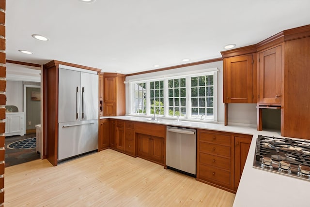 53 Beach Ave, Kennebunk, ME 04043 - kitchen with stainless steel appliances, light wood-style flooring, light countertops, brown cabinets, and ornamental molding