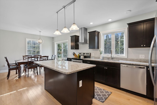 5 Harmony Way, Falmouth, ME 04105 - kitchen with stainless steel appliances, wall chimney exhaust hood, a center island, light stone counters, and light wood-style floors