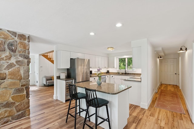 2 Far View Cir, Saco, ME 04072 - kitchen featuring stainless steel appliances, light wood-type flooring, white cabinets, a kitchen breakfast bar, and a kitchen island