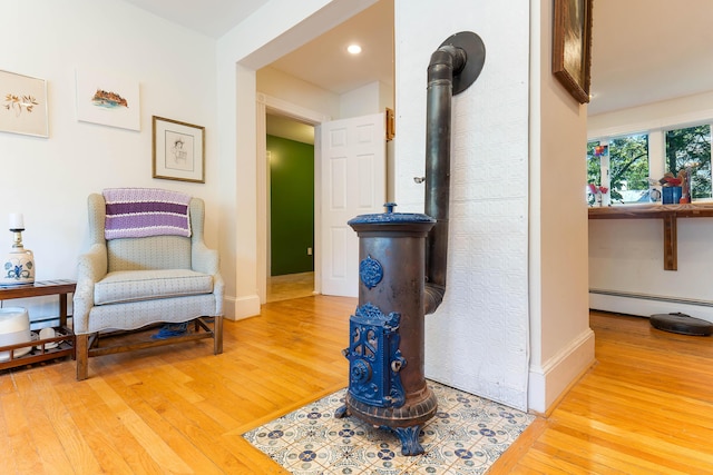 390 Front St, Bath, ME 04530 - sitting room with a baseboard heating unit, wood finished floors, recessed lighting, and a wood stove