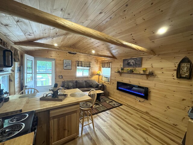 1093 N Chester Rd, Chester, ME 04457 - kitchen with a glass covered fireplace, light wood-style flooring, wooden walls, black range with electric stovetop, and open floor plan