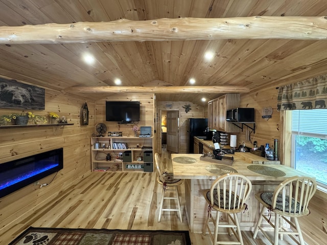 1093 N Chester Rd, Chester, ME 04457 - kitchen featuring wood finished floors, black appliances, wood walls, a glass covered fireplace, and a peninsula