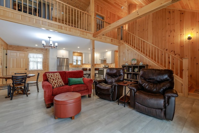 51 Short Point Way, Orland, ME 04472 - living area featuring wooden walls, stairway, a chandelier, a towering ceiling, and light wood finished floors