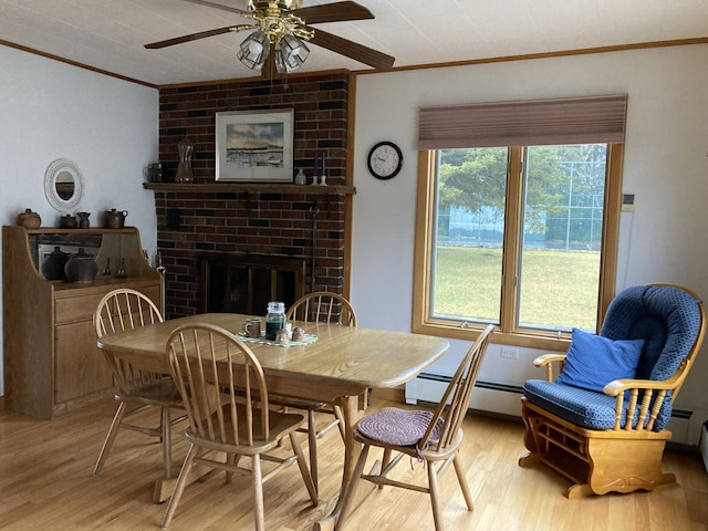 1 Francis Rd, Steuben, ME 04680 - dining area featuring ornamental molding, a baseboard radiator, light wood-type flooring, ceiling fan, and a brick fireplace