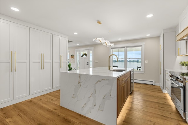 352 River Rd, Eliot, ME 03903 - kitchen with high end stainless steel range oven, a center island with sink, light wood-style flooring, a baseboard heating unit, and white cabinets