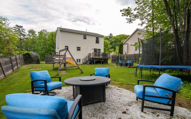 9 St James Pl, Lewiston, ME 04240 - fenced backyard with a trampoline, a playground, a fire pit, and a wooden deck