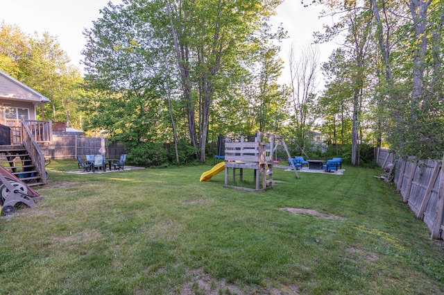 9 St James Pl, Lewiston, ME 04240 - fenced backyard featuring a playground, a wooden deck, stairs, and a fire pit