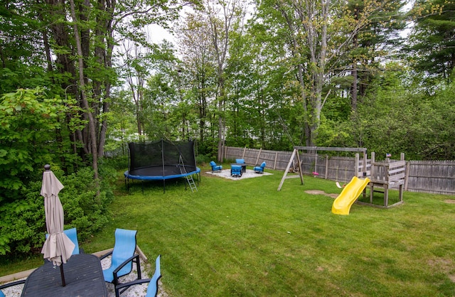 9 St James Pl, Lewiston, ME 04240 - fenced backyard featuring a playground, a trampoline, a patio area, and an outdoor fire pit