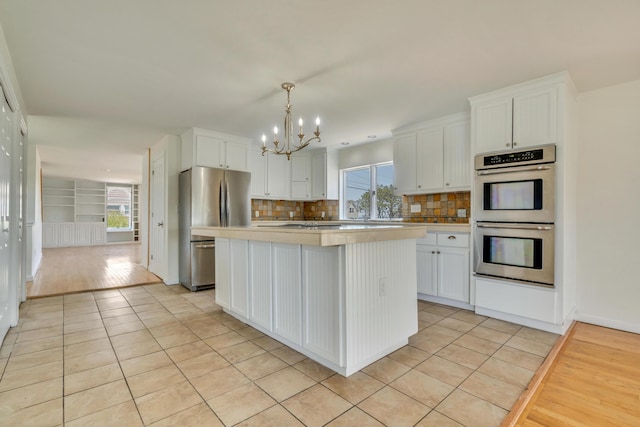 9 Riverside Ave, Saco, ME 04072 - kitchen featuring stainless steel appliances, a chandelier, decorative backsplash, light tile patterned flooring, and light countertops