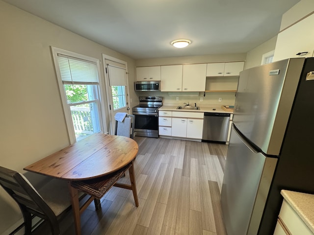 25 Minott St Unit 9, South Portland, ME 04106 - kitchen featuring appliances with stainless steel finishes, light countertops, light wood-style floors, white cabinets, and open shelves