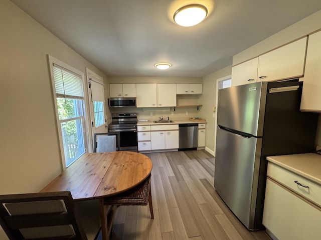 25 Minott St Unit 9, South Portland, ME 04106 - kitchen with stainless steel appliances, light countertops, light wood-type flooring, white cabinetry, and open shelves