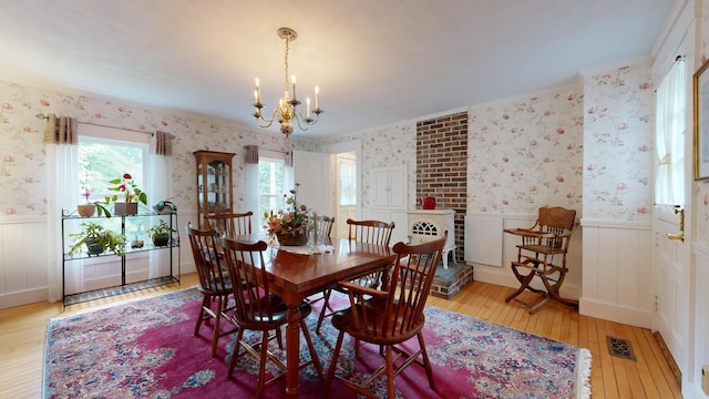 486 Webbs Mills Rd, Raymond, ME 04071 - dining space with wallpapered walls, wainscoting, light wood finished floors, and a chandelier
