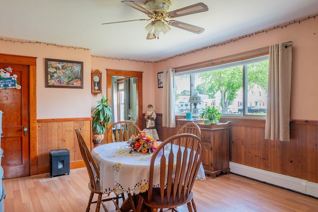 11 Gertrude Ave, Biddeford, ME 04005 - dining area with a baseboard heating unit, light wood-type flooring, a wainscoted wall, wood walls, and ceiling fan