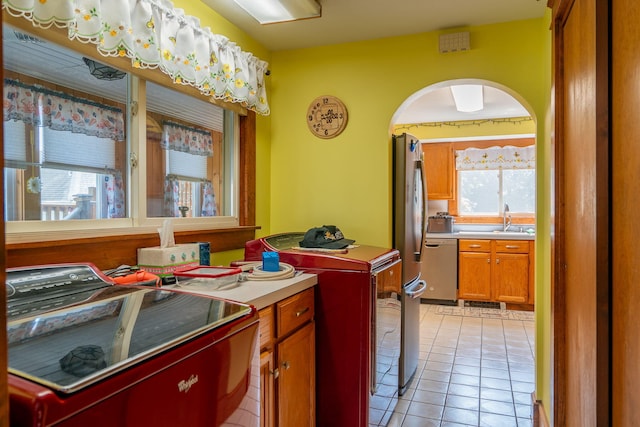 11 Gertrude Ave, Biddeford, ME 04005 - kitchen featuring arched walkways, stainless steel dishwasher, washer and dryer, light tile patterned floors, and light countertops
