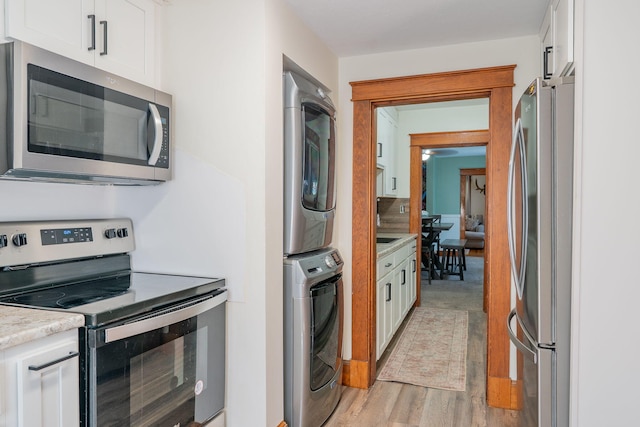 11 Gertrude Ave, Biddeford, ME 04005 - kitchen featuring appliances with stainless steel finishes, stacked washer / dryer, white cabinetry, light countertops, and light wood-style flooring