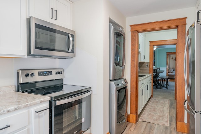 11 Gertrude Ave, Biddeford, ME 04005 - kitchen with stainless steel appliances, estacked washer and dryer, white cabinetry, and light wood-style floors