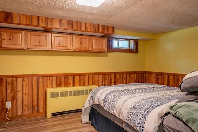 11 Gertrude Ave, Biddeford, ME 04005 - bedroom featuring radiator heating unit, a textured ceiling, light wood-style floors, a wainscoted wall, and wooden walls