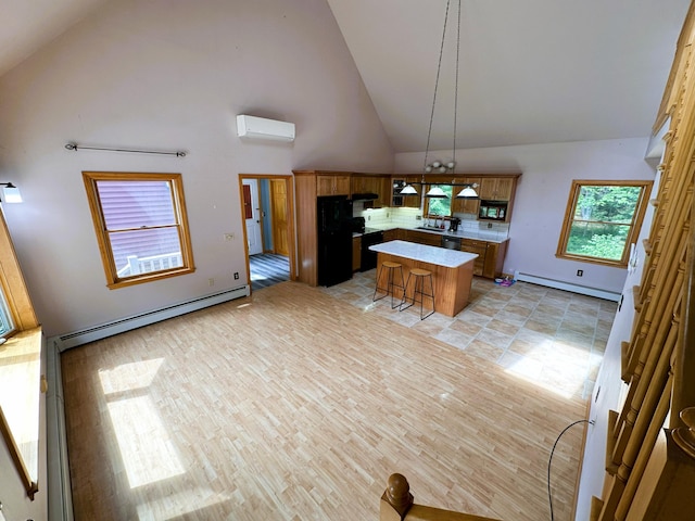 27 Hodgdon Rd, Levant, ME 04456 - kitchen with a baseboard heating unit, a wall mounted AC, a center island, high vaulted ceiling, and a kitchen breakfast bar