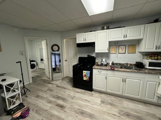 46 Cedar St, Dover-Foxcroft, ME 04426 - kitchen featuring black range oven, white microwave, extractor fan, a paneled ceiling, and white cabinetry