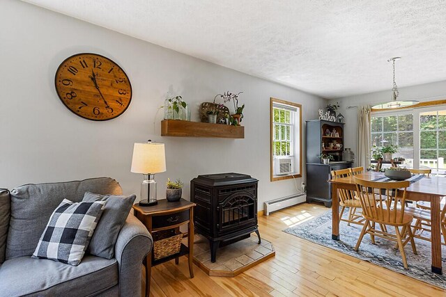 34 Cari Way, Sidney, ME 04330 - dining area featuring a wood stove, a baseboard radiator, a textured ceiling, light wood-type flooring, and cooling unit