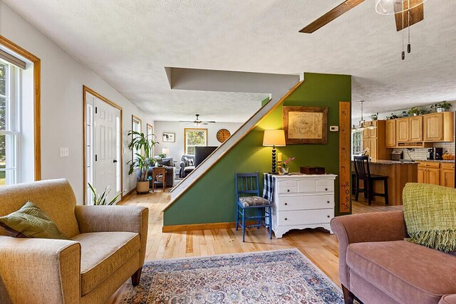 34 Cari Way, Sidney, ME 04330 - living room with ceiling fan, plenty of natural light, light wood-style flooring, a textured ceiling, and stairs