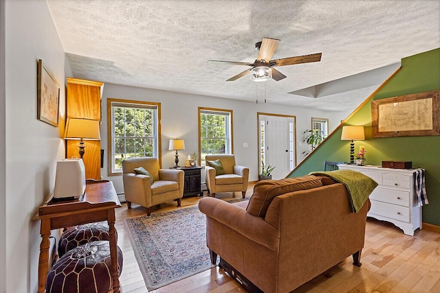 34 Cari Way, Sidney, ME 04330 - living room featuring a textured ceiling, light wood-style floors, a ceiling fan, and a baseboard radiator
