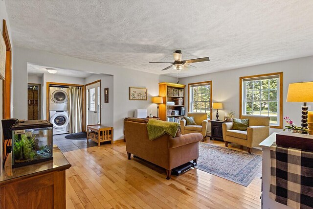 34 Cari Way, Sidney, ME 04330 - living room featuring stacked washing machine and dryer, a textured ceiling, ceiling fan, and light wood-type flooring