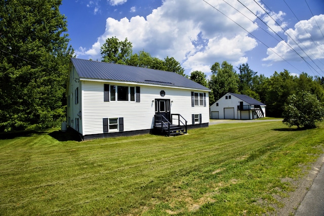 199 Middle Rd, Bradford, ME 04410 - back of property with a garage, a lawn, an outbuilding, a metal roof, and view of scattered trees