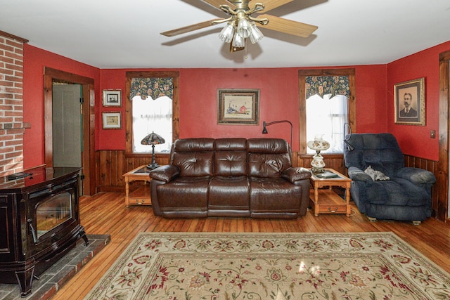 133 Hio Ridge Rd, Bridgton, ME 04009 - living room featuring wood-type flooring, a wood stove, plenty of natural light, a ceiling fan, and a wainscoted wall